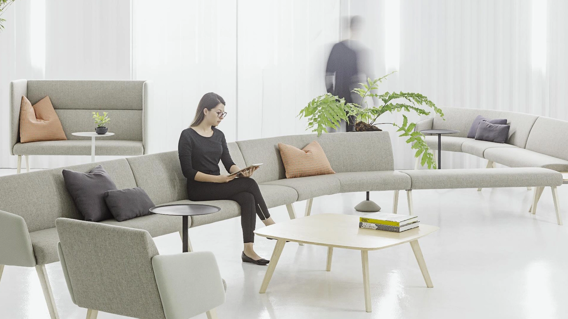Área de descompressão com sofás modulares, poltronas e almofadas em tons neutros