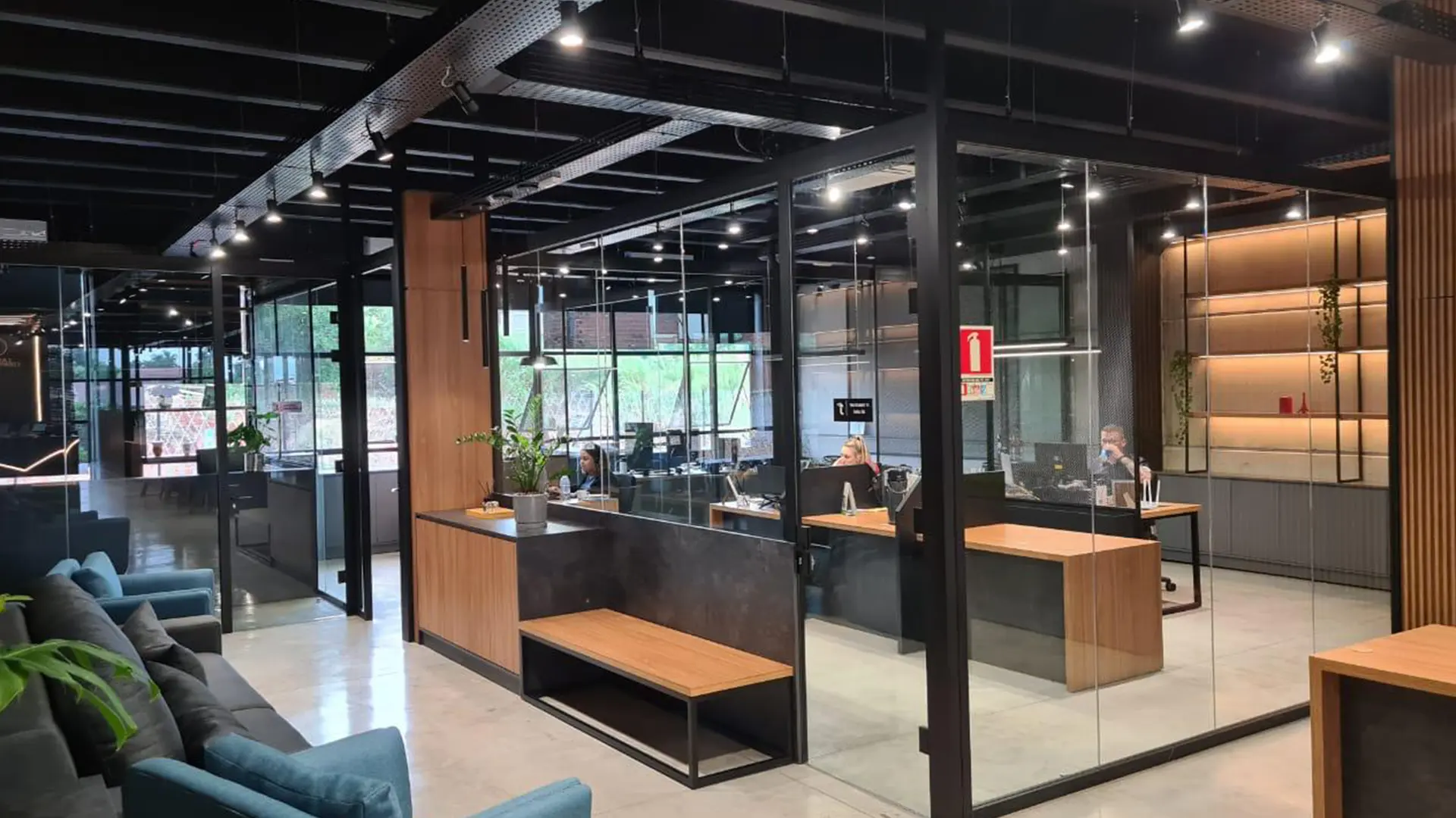 Recepção com estrutura metálica e divisórias de vidro em ambiente industrial